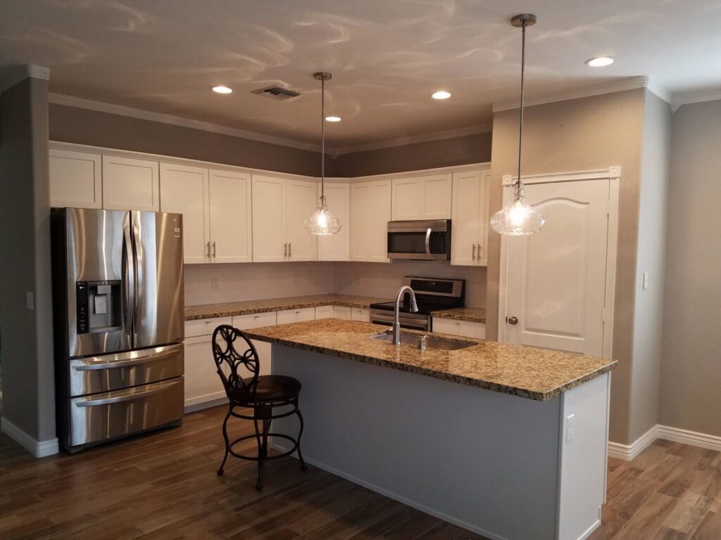A newly renovated modern kitchen featuring white cabinets, granite countertops, and stainless steel appliances by Rapid Restoration and Construction in Mesa, AZ.