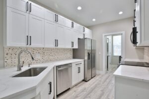 A modern kitchen renovation featuring white cabinets, stainless steel appliances, and mosaic backsplash by ALKA Construction/ Handyman Services in Layton, UT