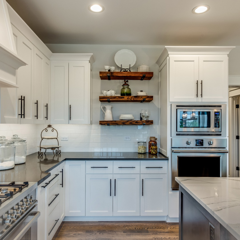 A modern kitchen renovation with white cabinets, dark countertops, and wooden shelves by Build Simple in Sterling, MA.