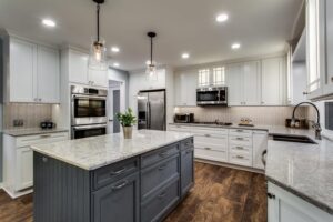A modern renovated kitchen featuring white cabinets, a grey island, and new appliances by RepairTo Roofing, Renovations & Repairs in Wilmington, DE.