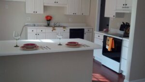 A completed modern kitchen renovation with white cabinets and black appliances by Unique Construction Services in Knoxville, TN