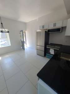 A modern kitchen renovation with white tile flooring and new appliances completed by Modern Image Construction LLC in El Paso, TX.