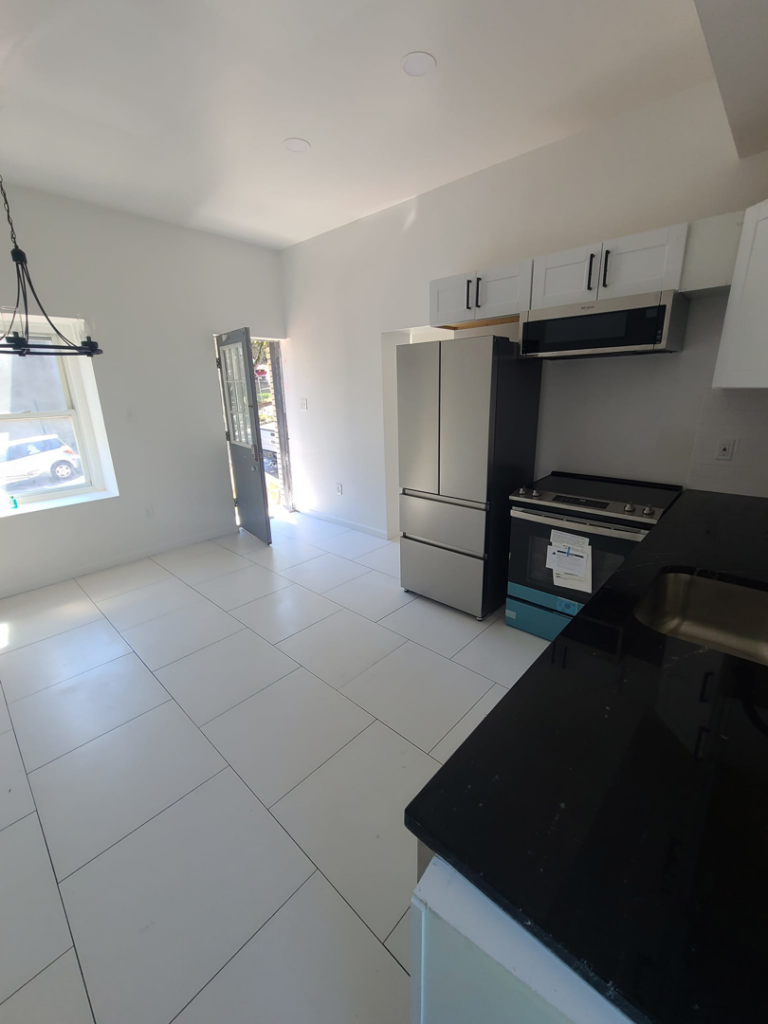 A modern kitchen renovation with white tile flooring and new appliances completed by Modern Image Construction LLC in El Paso, TX.