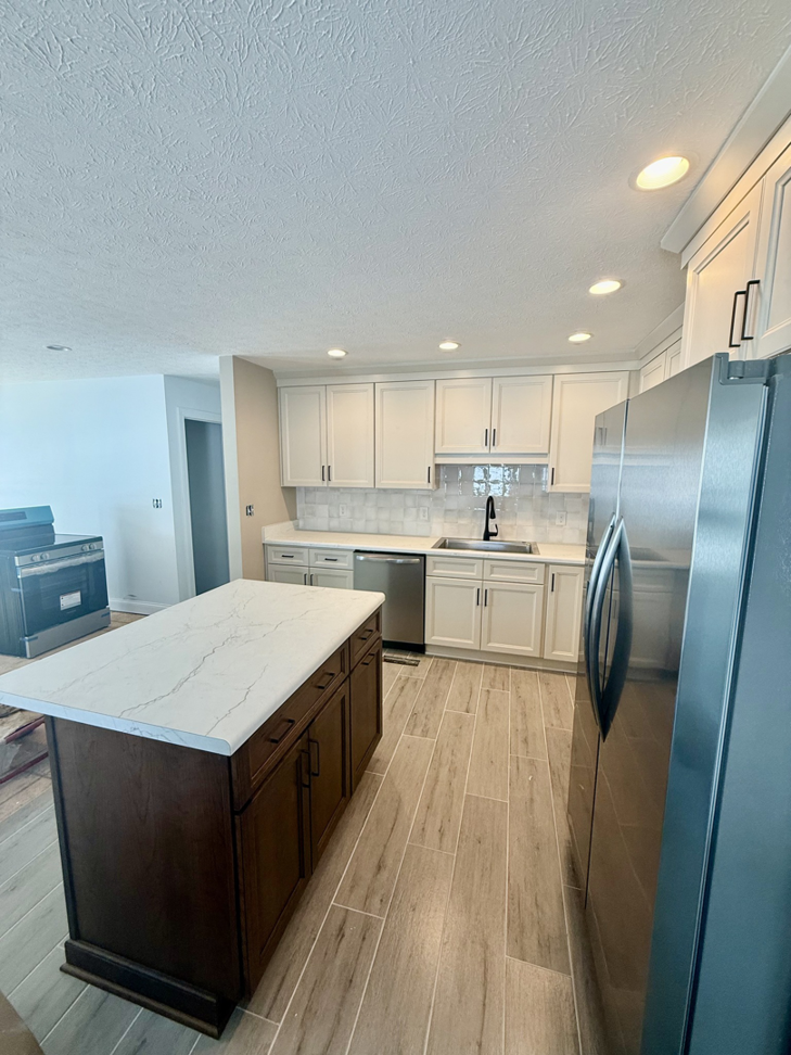 A modern kitchen renovation featuring new cabinets, an island, and stainless steel appliances, completed by Phillips Homes, LLC in Elizabethtown, KY.