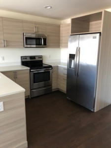 Modern kitchen renovation showcasing new light-colored cabinets and stainless steel appliances by MTI Carpentry in Jersey City, NJ.