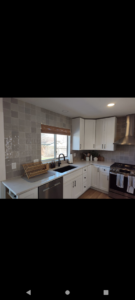 A modern kitchen sink area with white cabinets and light gray backsplash, installed by Layvic Construction LLC in Downtown Denver, CO