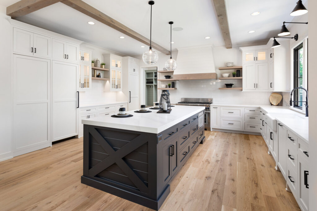 A modern kitchen with white cabinets, a large dark island, and wood beams, a renovation by Autumn Homes in Naperville, IL.
