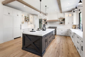 A modern kitchen with white cabinets, a large dark island, and wood beams, a renovation by Autumn Homes in Naperville, IL.