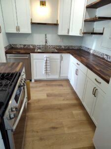 A modern kitchen remodel with white cabinets, warm wood countertops, and a decorative backsplash by Lay's Remodeling LLC in El Paso, TX
