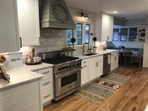 A modern kitchen featuring white cabinets, subway tile backsplash, and stainless steel appliances by Technically Aesthetic General Contractors in Johnson City, TN.