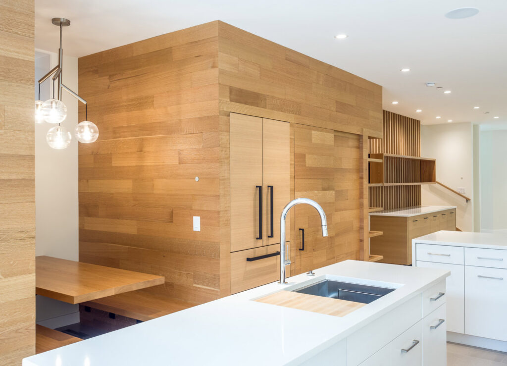A modern kitchen featuring extensive wood paneling, integrated appliances, and a large island by S.N. Peck Builder, Inc. in Chicago, IL.