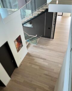 Modern light wood flooring and glass staircase installation by Santizo Flooring & Painting in Raleigh, NC.