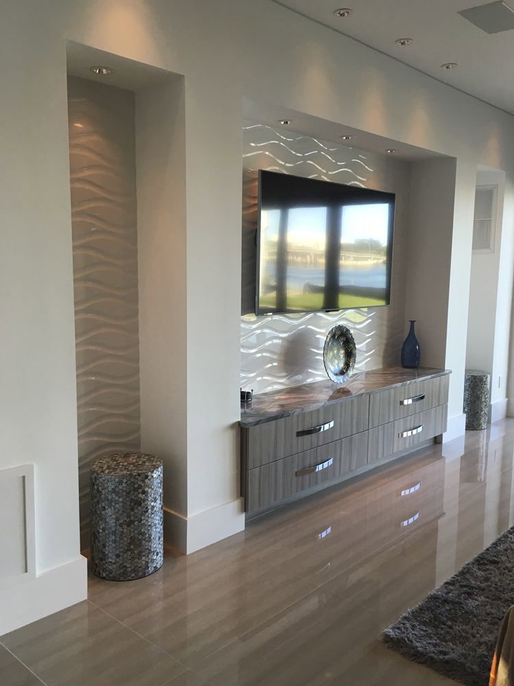 Modern living area with a wall-mounted TV and decorative wall paneling by Charter Bay Home Builders in Tampa, FL