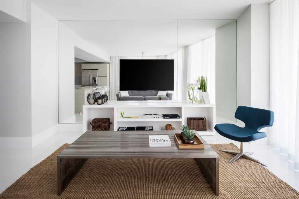 A modern living room interior with a large television, sleek console, and contemporary furniture, remodeled by JNY Remodeling INC in Fort Lauderdale, FL.