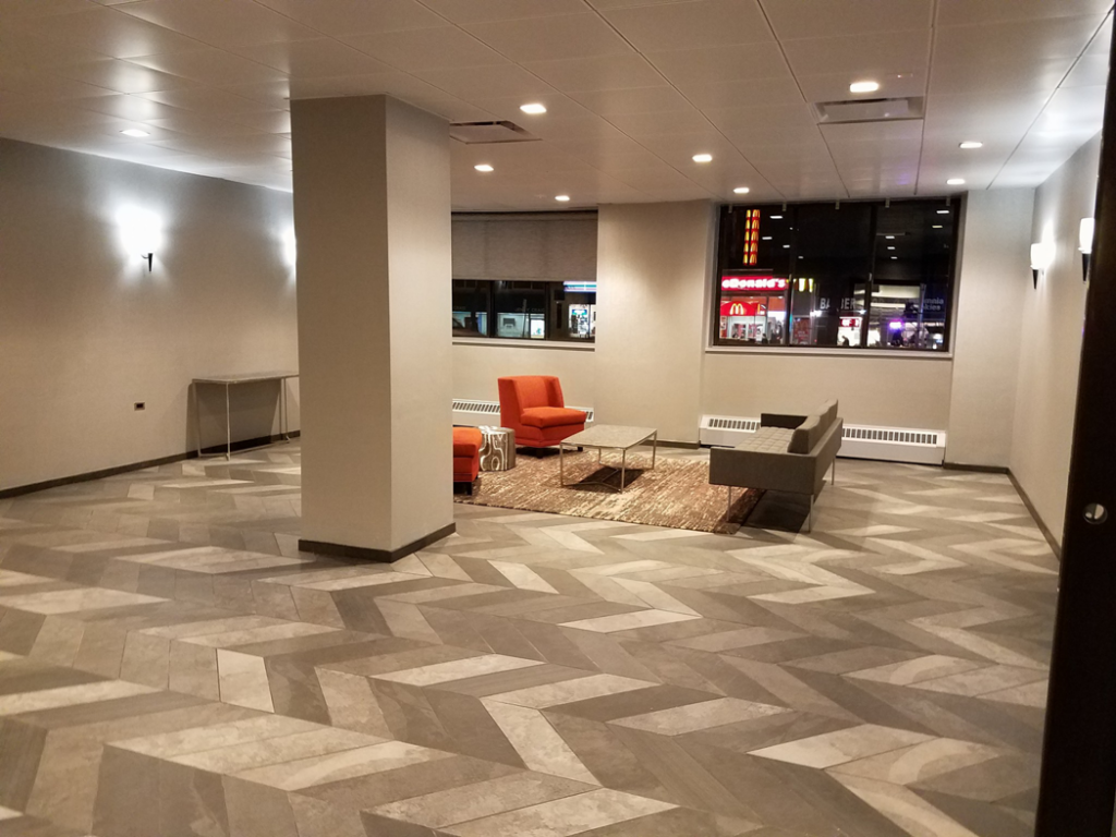 A newly renovated modern lobby area with herringbone tile flooring and contemporary furniture by HnM Builders in Knoxville, TN