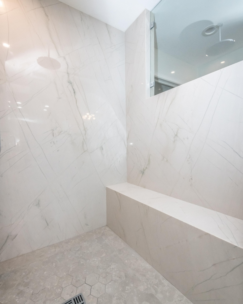 A modern shower featuring elegant white marble or granite walls and a built-in bench by Accent Marble & Granite, Inc in Phoenix, AZ
