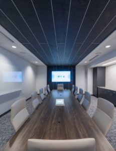 A modern office conference room with a large table and screen, showcasing a commercial build-out by Drash Contracting Company LLC in San Antonio, TX.
