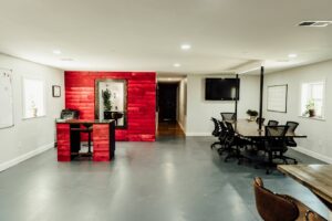 A modern office space featuring a striking red accent wall and a large meeting table, renovated by Huff Consolidated Enterprises LLC in Clarksville, TN.