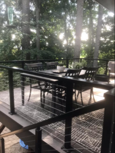 A modern outdoor deck with sleek cable railings and a dining set, built by Edge River Home Services in Springfield, OR.