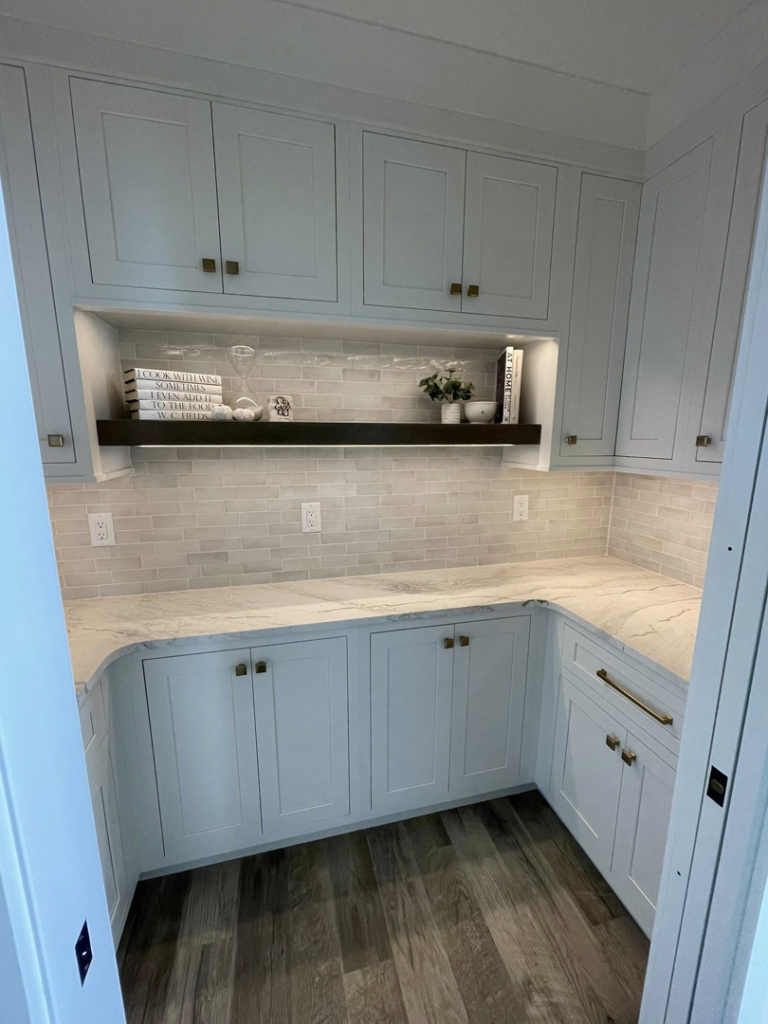 A modern pantry with white cabinets, marble countertops, and subway tile backsplash by Abbott Construction LLC in Boxford, MA.