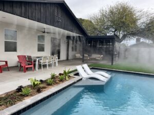 A high-quality mist system installed on a modern patio with a pool and lounge chairs by Mr. Mister in Surprise, AZ