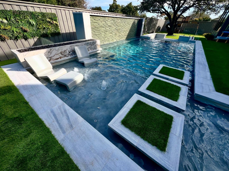 A modern rectangular pool with sun shelf, water wall, and turf stepping stones by First Class Pools & Spas in Sachse, TX.