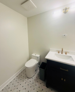 A completed modern powder room renovation with a black vanity and patterned floor tiles by All In Service Group, LLC in Chicago, IL.