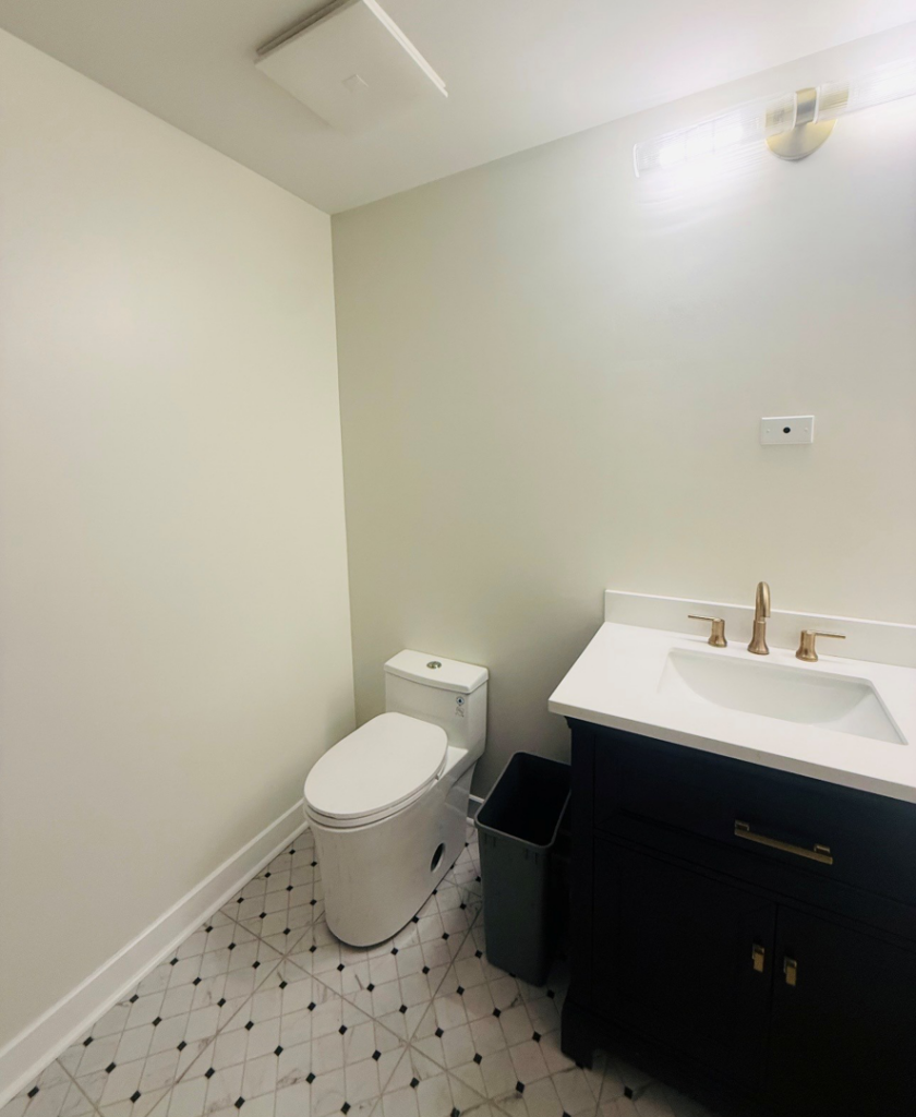 A completed modern powder room renovation with a black vanity and patterned floor tiles by All In Service Group, LLC in Chicago, IL.