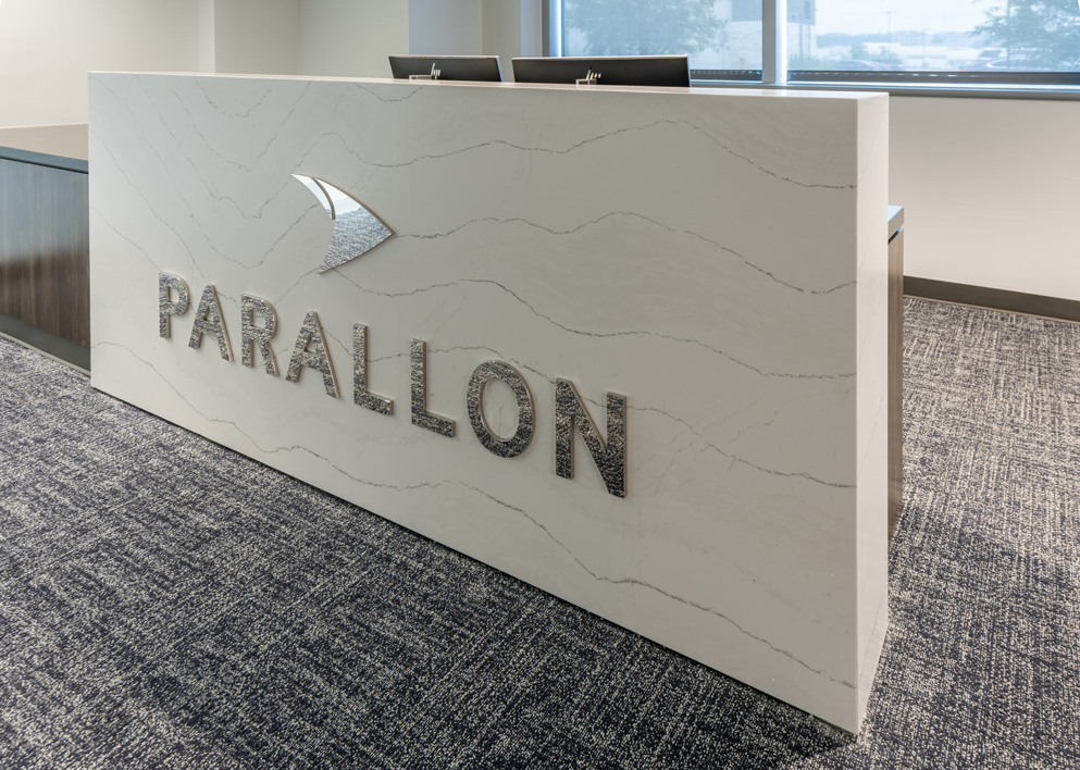 A modern reception desk in a commercial interior space, showcasing a completed project by Drash Contracting Company LLC in San Antonio, TX.