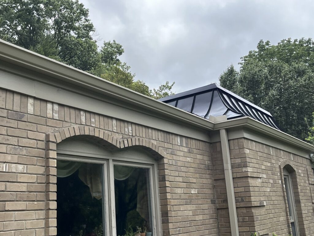 A brick house showcasing a modern black roof feature or skylight installed by Music City Exteriors in Nashville, TN