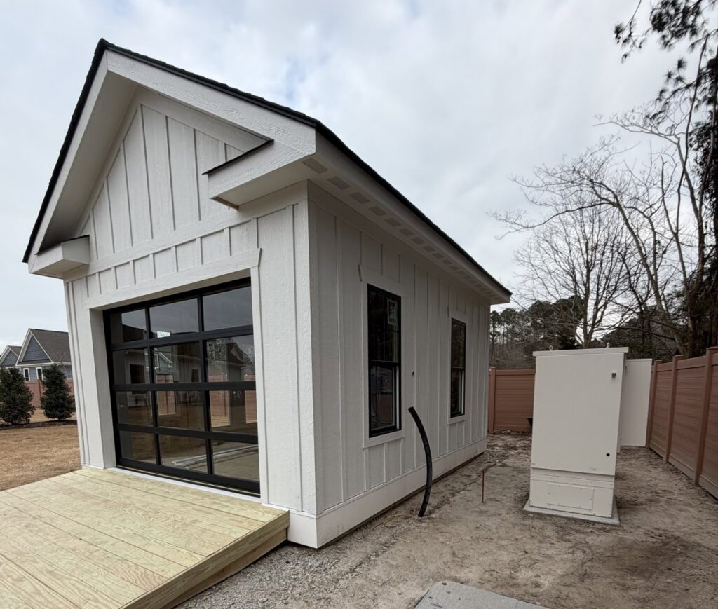 Newly constructed modern shed or outbuilding with a glass garage door by BOS HOME Exterior Services in Virginia Beach, VA