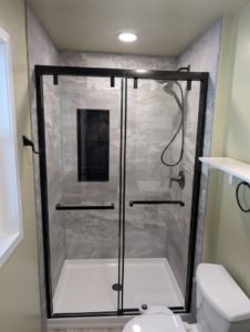 A modern shower enclosure with black frame and tiled walls installed by A&A Property Renovations LLC in Green Bay, WI.