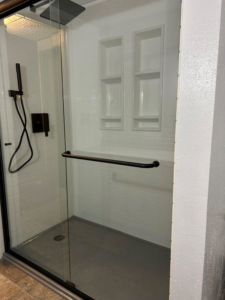 A modern shower enclosure with a glass door and black fixtures installed by VanVleet Construction in Brooklyn Park, MN.