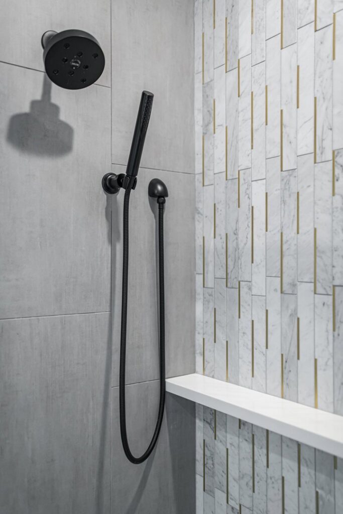 A modern black shower head and handheld sprayer installed in a tiled shower by Thimijan Custom Homes LLC in Rochester, MN