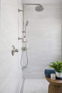A modern shower head and handheld sprayer installed in a tiled shower by Forma Builders Bend in Bend, OR.