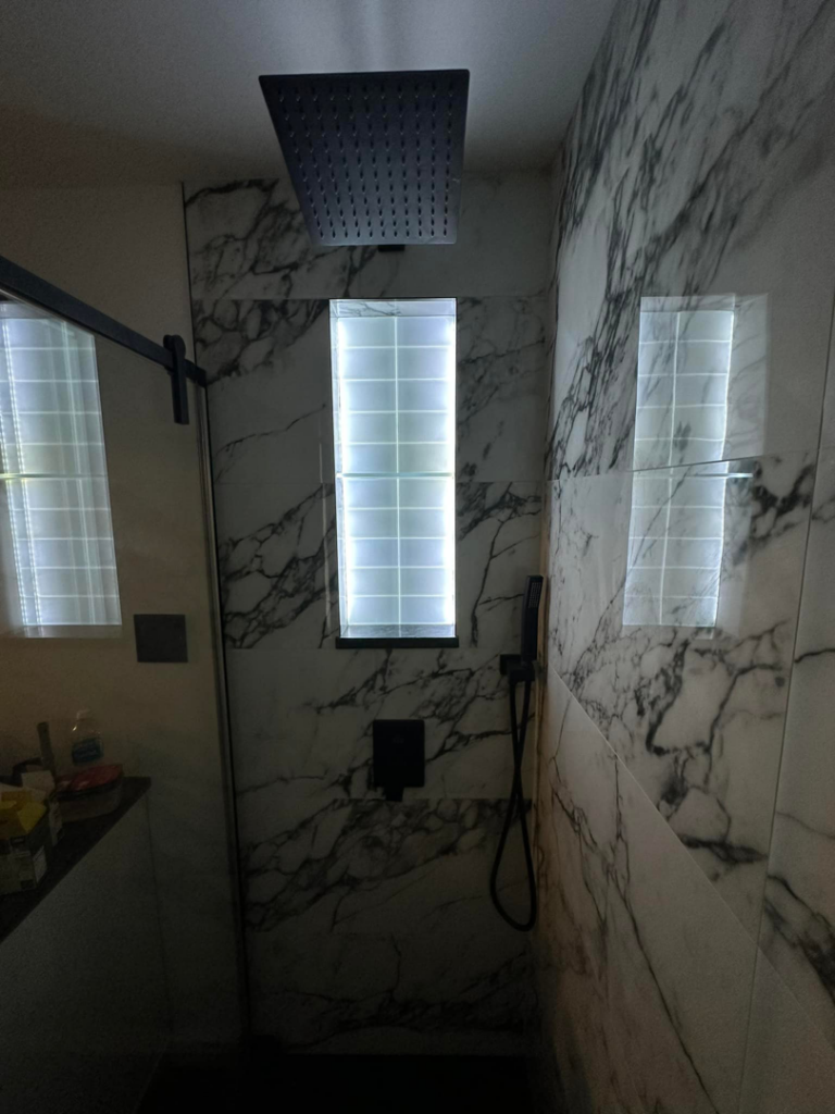A modern shower renovation featuring marble-look tiles and a rain shower head by Tap & Tile Inc. in East Pittsburgh, PA.