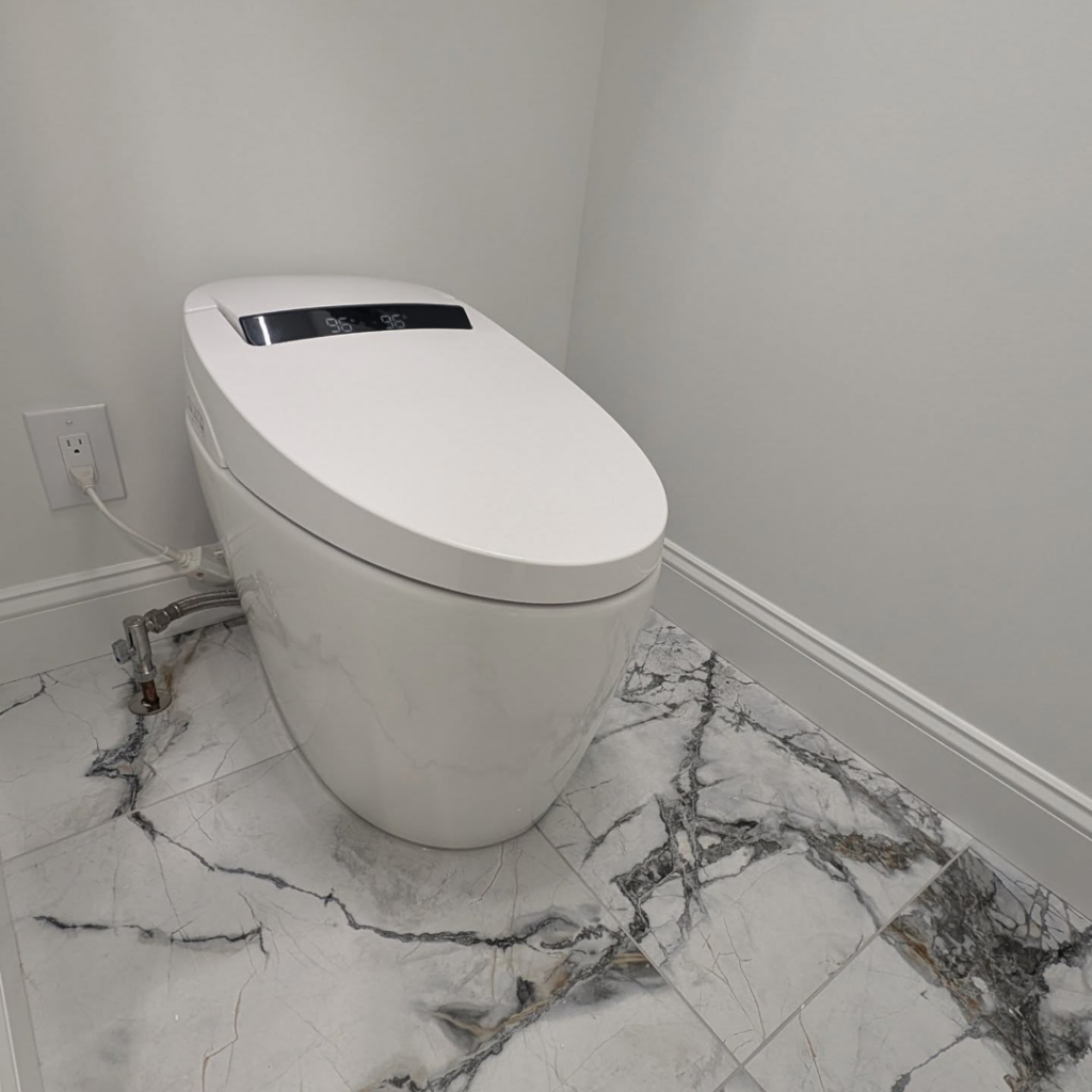 A modern smart toilet installed on new marble-look tiled flooring by Ensotile - Atlanta Bathroom Remodeling in Stone Mountain, GA