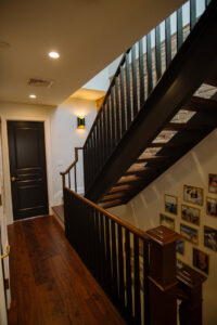 A modern staircase with dark wood and metal railings, featuring recessed lighting, installed by Connaughton Construction in Waltham, MA