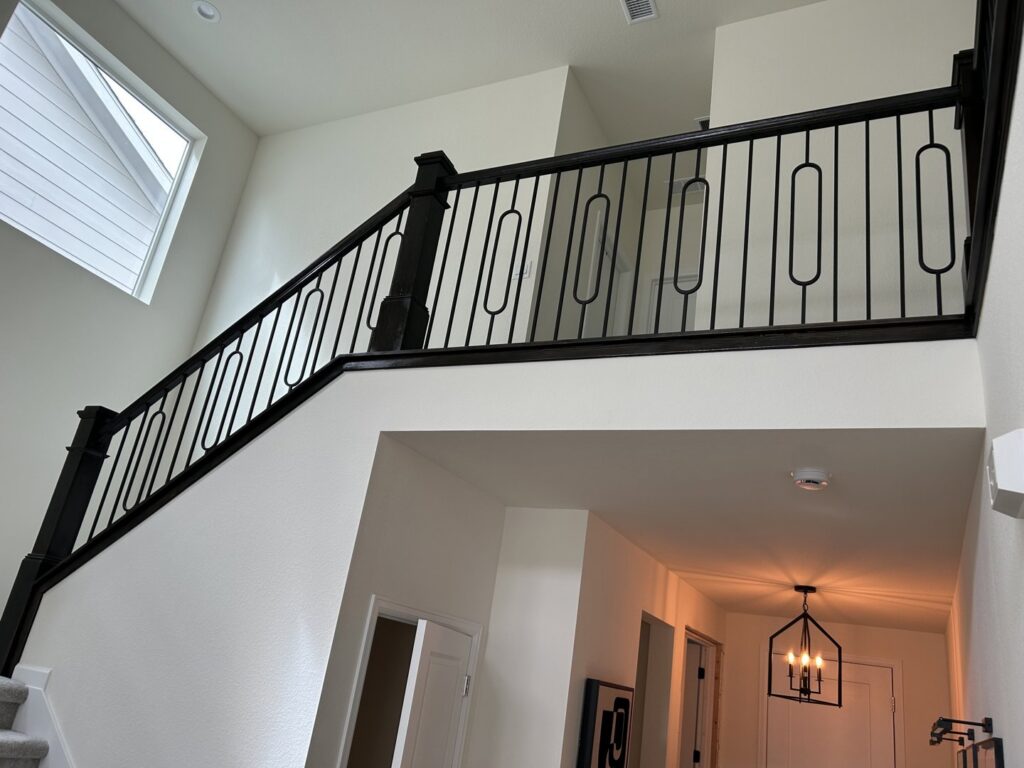 A modern staircase featuring black metal railings, a renovation project completed by Wam Bam Handyman LLC in Colorado Springs, CO
