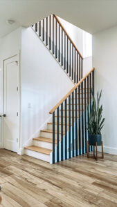 A modern staircase with wooden steps and sleek black railings, showcasing craftsmanship by Pioneer Built in St. Petersburg, FL.
