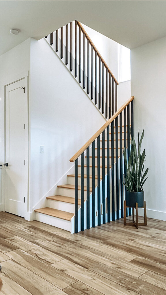 A modern staircase with wooden steps and sleek black railings, showcasing craftsmanship by Pioneer Built in St. Petersburg, FL.