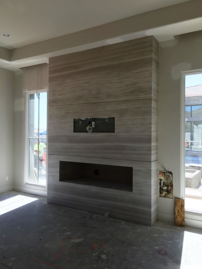 A modern stone fireplace surround under construction, installed by L&M Granite Countertops in Phoenix, AZ.