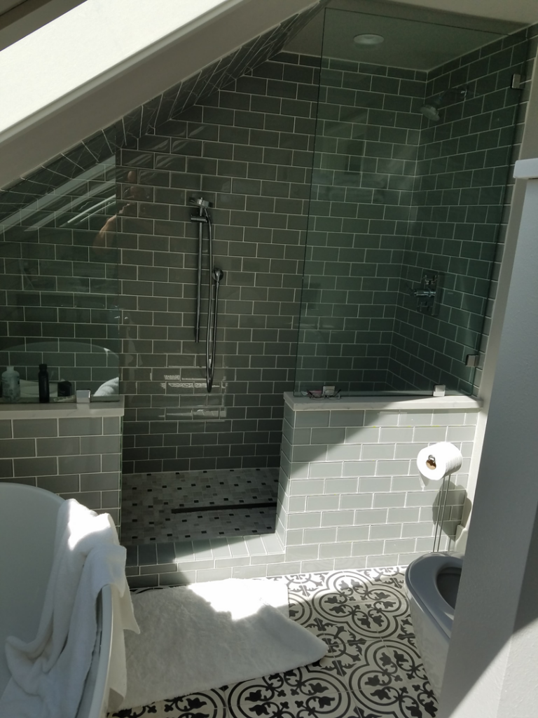 A modern tiled bathroom featuring a walk-in shower and glass enclosure, completed by Integrity Construction Group in Tacoma, WA.