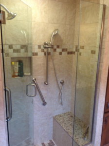 A modern tiled shower enclosure with glass door and built-in bench by Kingdom Advance Construction in Louisville, KY