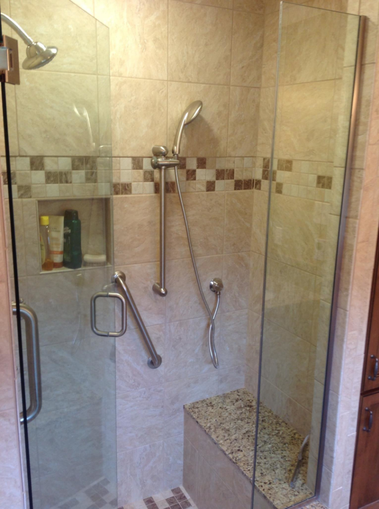 A modern tiled shower enclosure with glass door and built-in bench by Kingdom Advance Construction in Louisville, KY