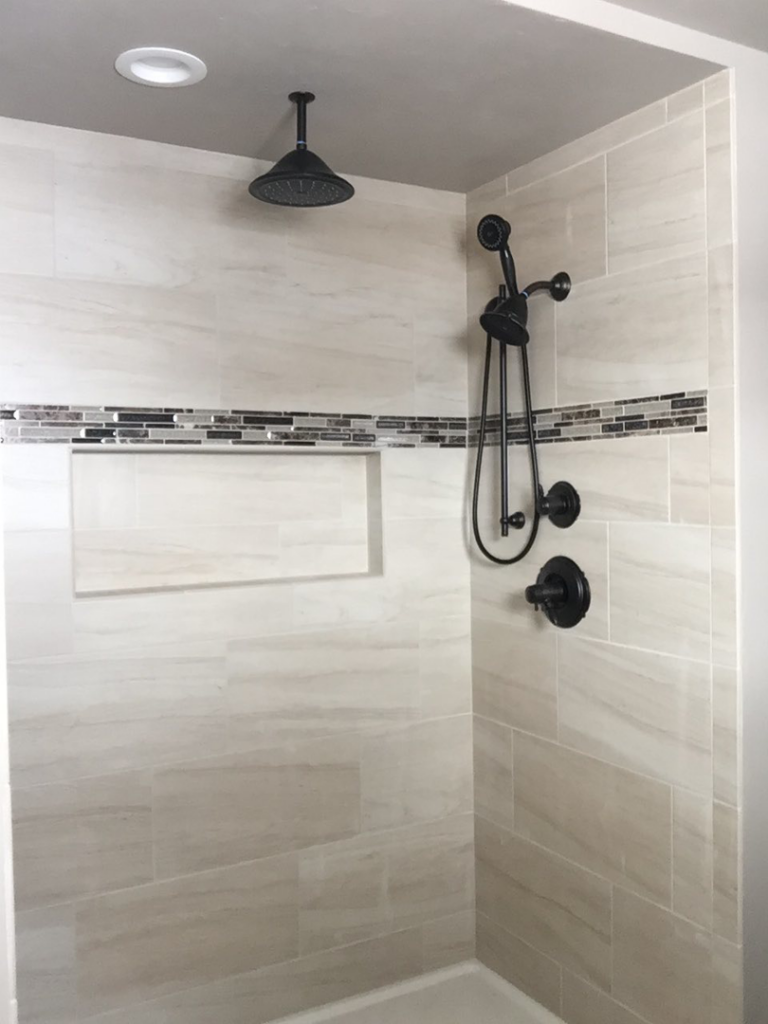 A modern tiled shower with new black fixtures and a mosaic accent installed by Fueled Up Flooring- Justin Watruba in Eau Claire, WI.