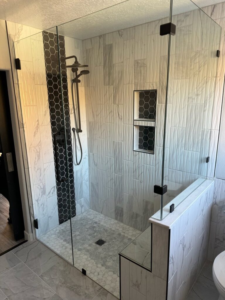 A modern tiled shower with a glass enclosure and hexagonal accent tiles, completed by Devco Construction LLC in West Valley City, UT