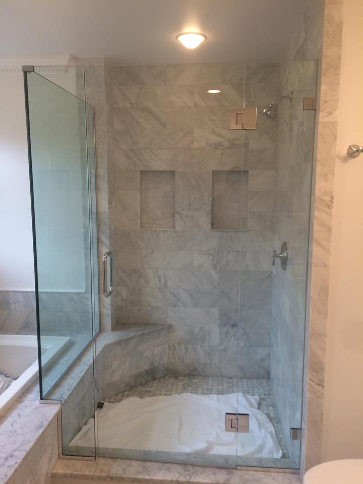 A modern tiled shower with a glass enclosure and built-in bench by Prenga Remodeling in Orange, CT