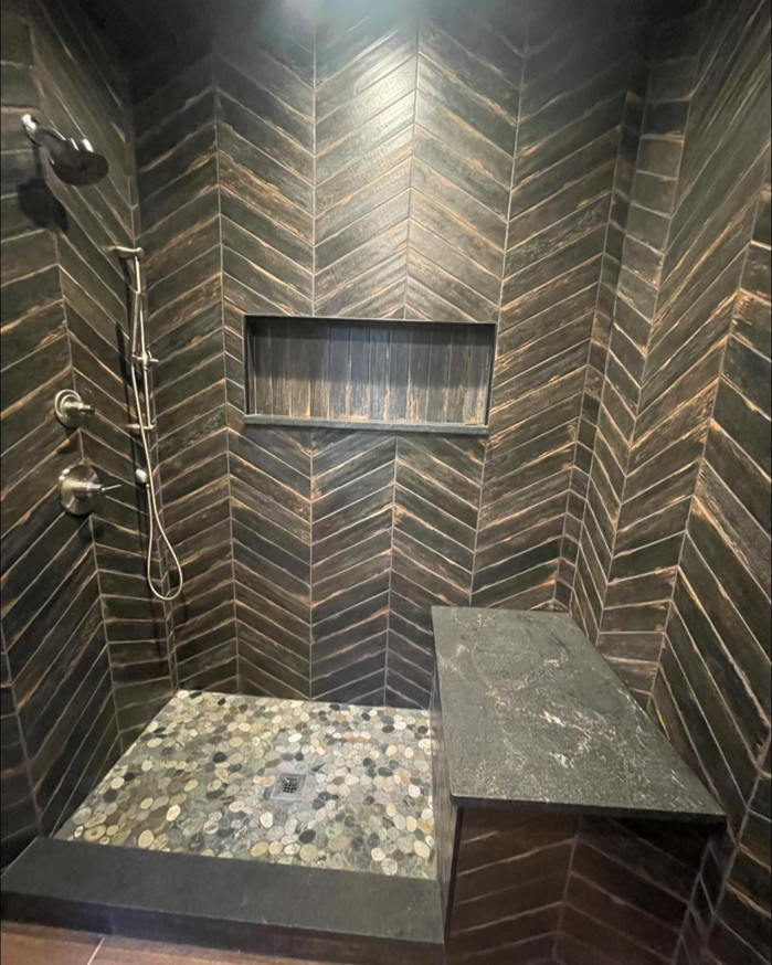 A modern tiled shower with herringbone wall tiles and a pebble floor by A&L Tile LLC in San Diego, CA