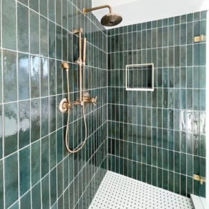 A modern tiled shower with dark green vertical tiles and gold fixtures installed by Buerger Brothers Construction in Lakewood, CO.